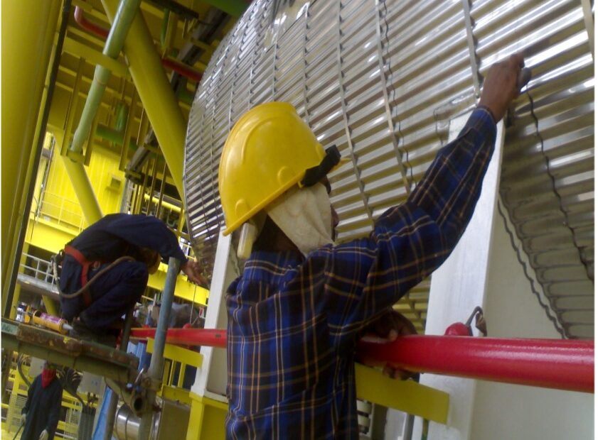 Lions Global construction workers in protective attire on site, working with corrugated cladding insulation.