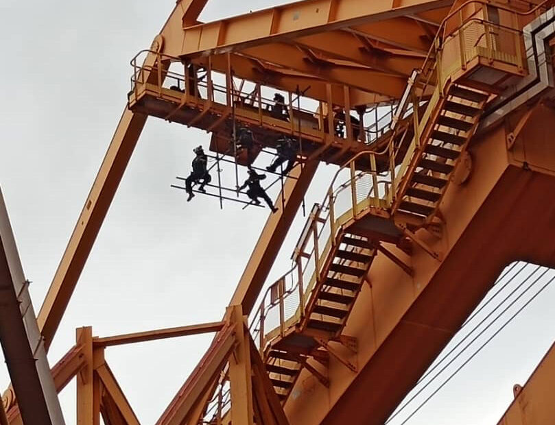 Four workers on a hanging scaffold, constructing Lions Global project with heavy-duty tubular material.