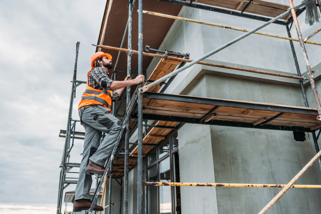 Skilled Lions Global worker scaling scaffolding at construction site.
