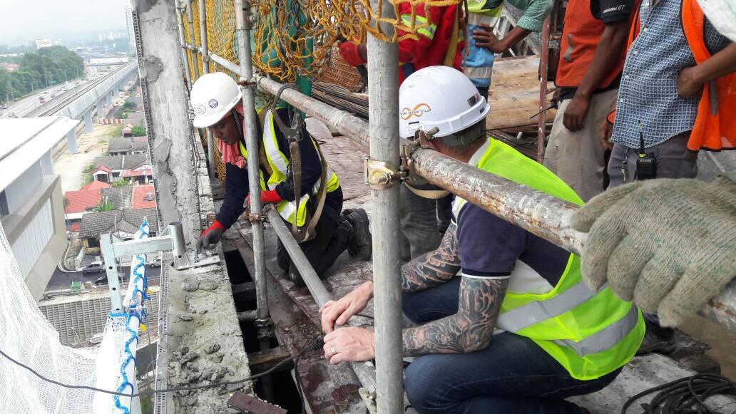 Lions Global construction workers installing safety catch net on a building site.