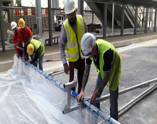 Five Lions Global construction workers installing safety catch net on project site.